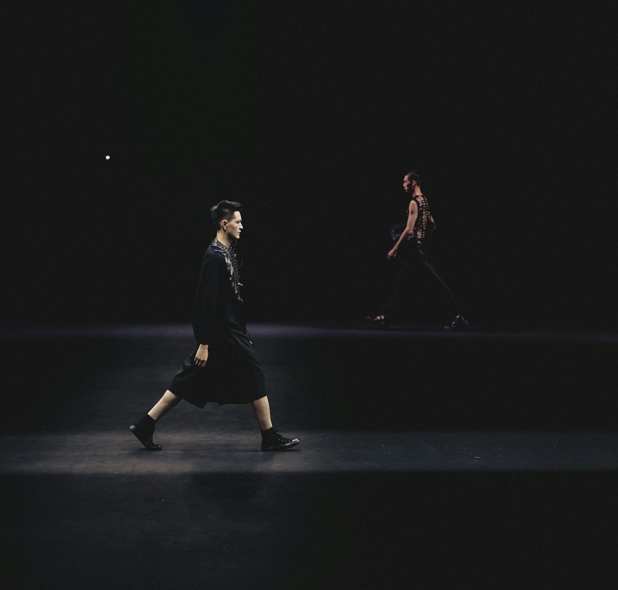Models walking a dark runway during a fashion show