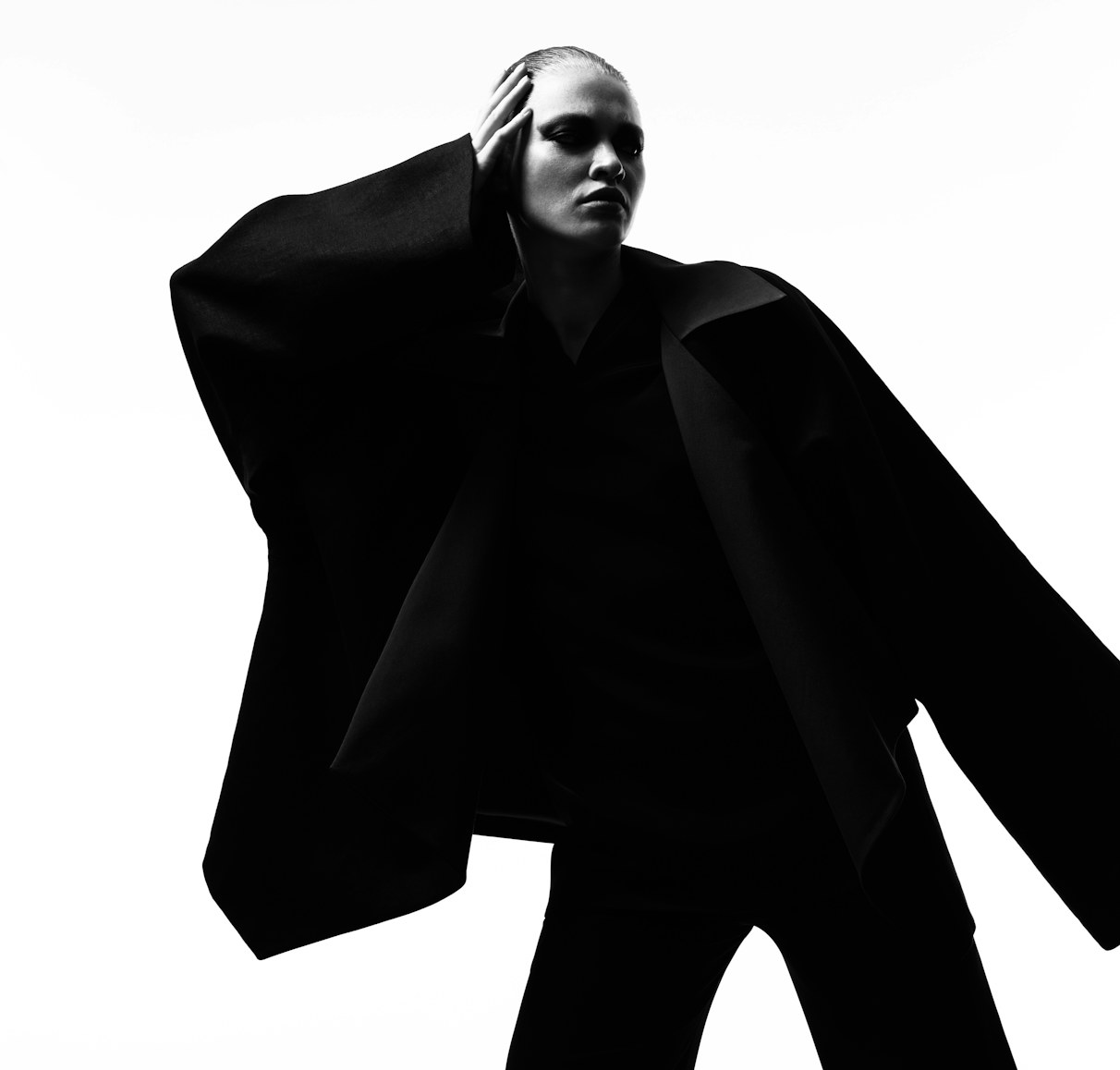 Model in a wide-sleeved black jacket posing in silhouette